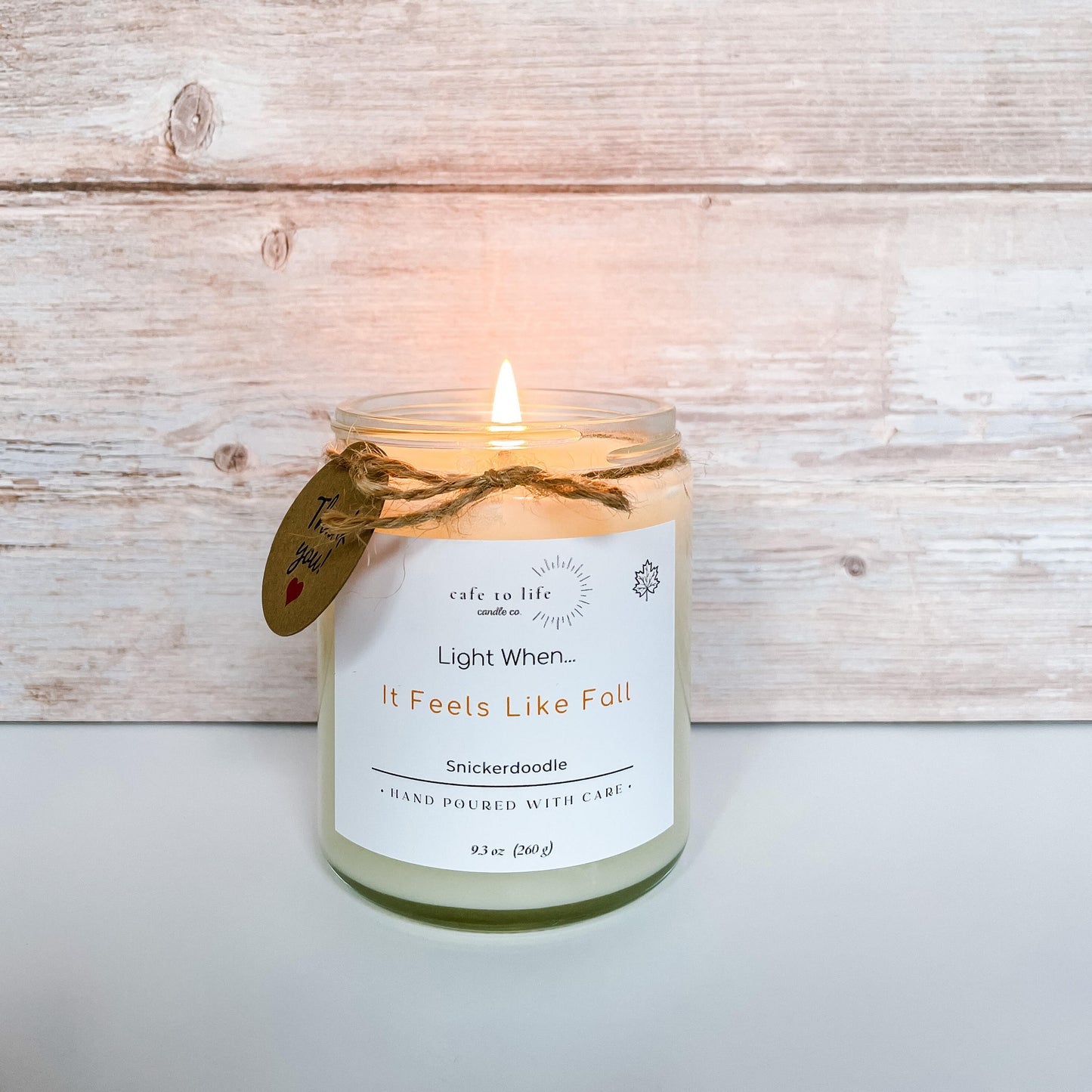 Lit candle with twine tied in a bow and a thank you tag. Label says "Light When... It Feels Like Fall"