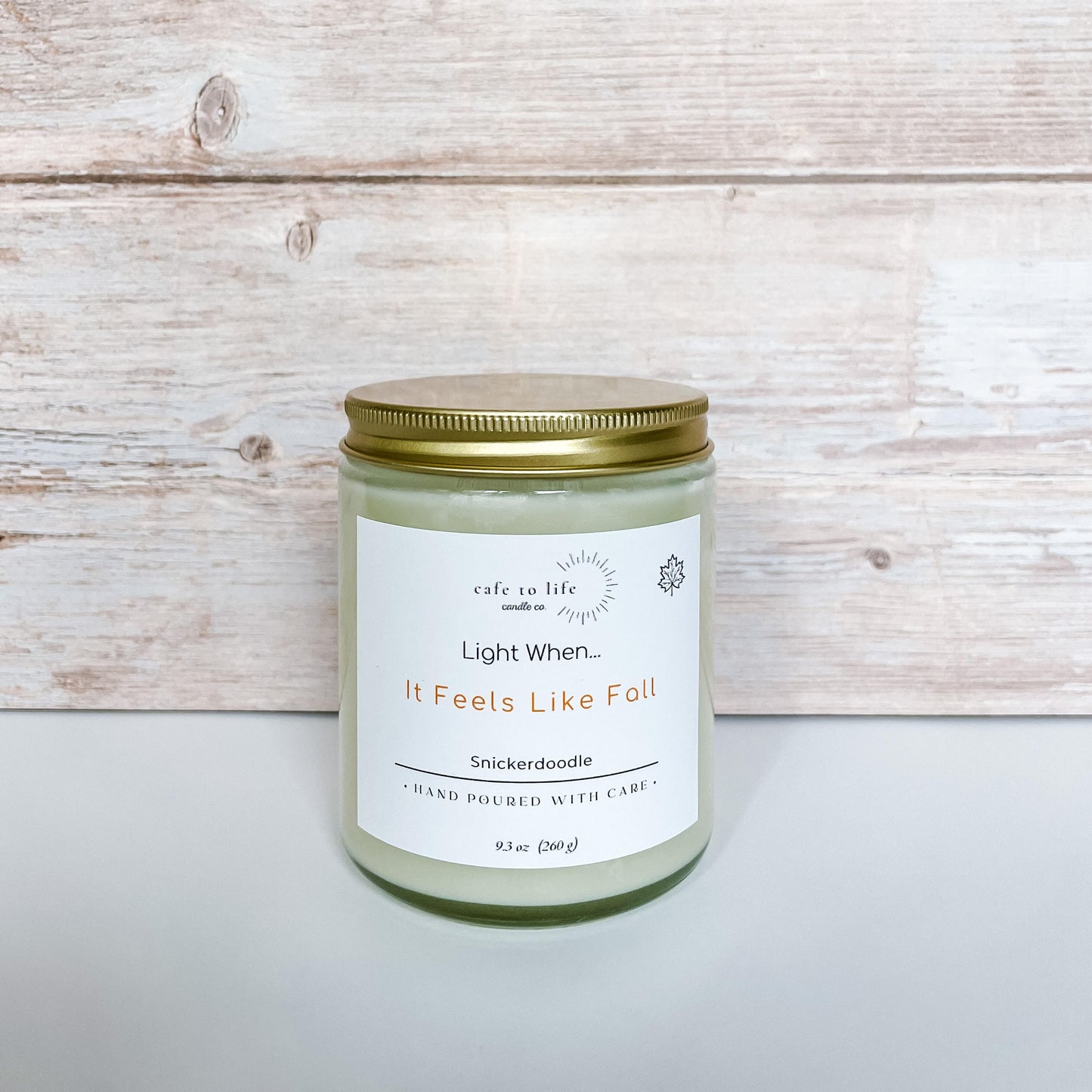 Candle in glass jar with gold top screwed on. Label says "Light When... It Feels Like Fall"
