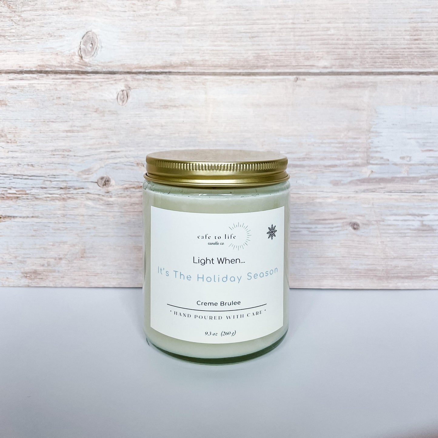 Glass candle with gold top screwed on. Label says, "Light When... It's The Holiday Season"