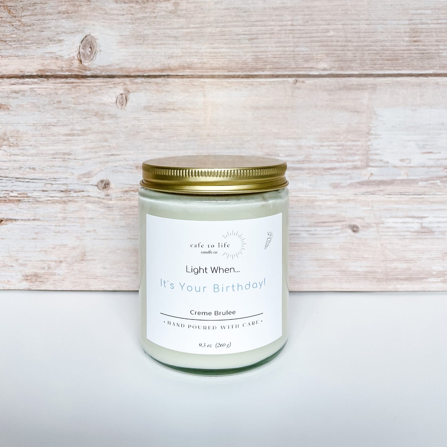 Glass candle with gold top screwed on. Label says, "Light When... It's Your Birthday!"