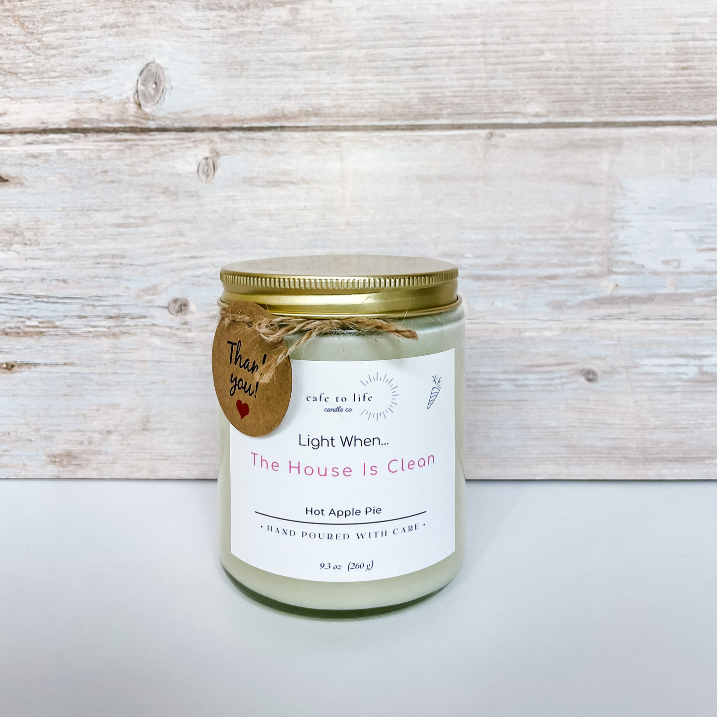 Candle with top on jar, twine tied in a bow, thank you tag. Label says, "Light When... The House Is Clean"