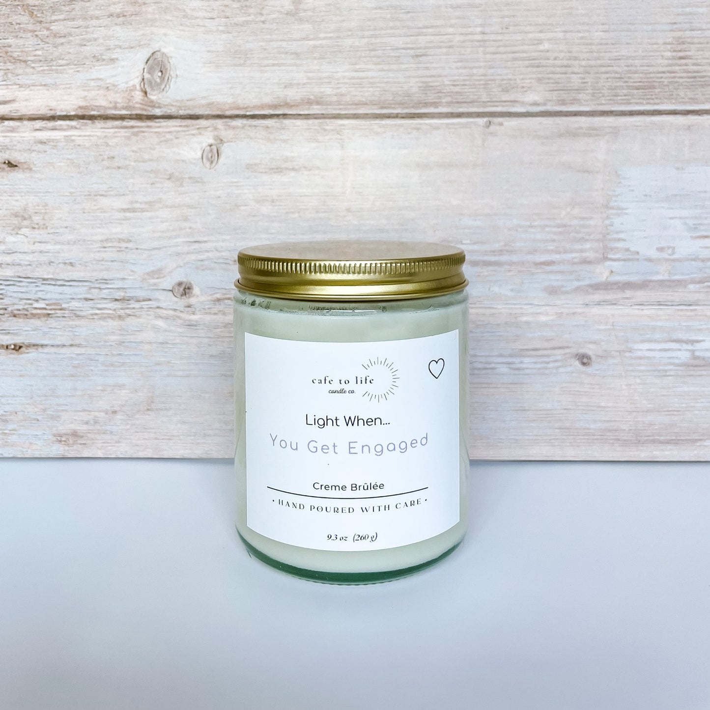 Glass candle jar with gold top. Label says, “Light When… You Get Engaged.” Heart in the corner of the label.