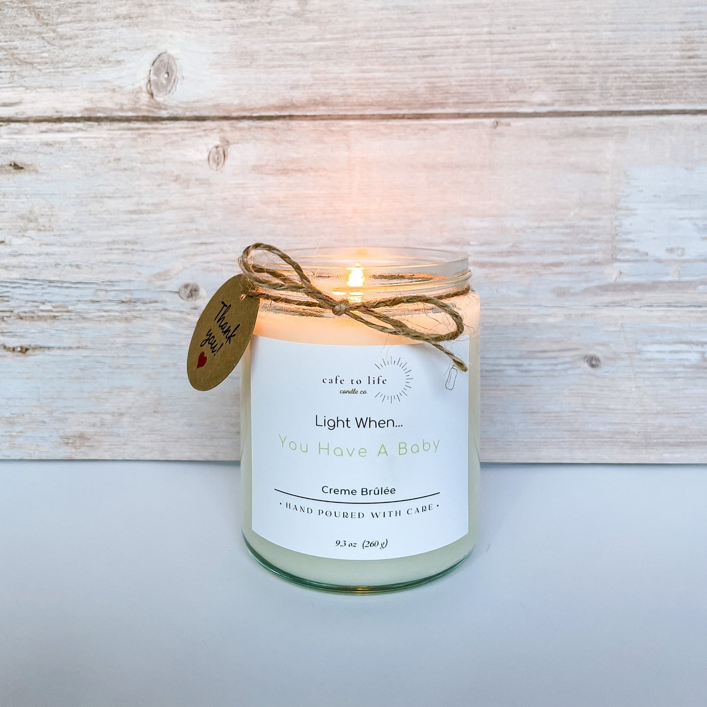 Lit candle with twine wrapped around it and a thank you tag. Label says, “Light When… You Have A Baby.”
