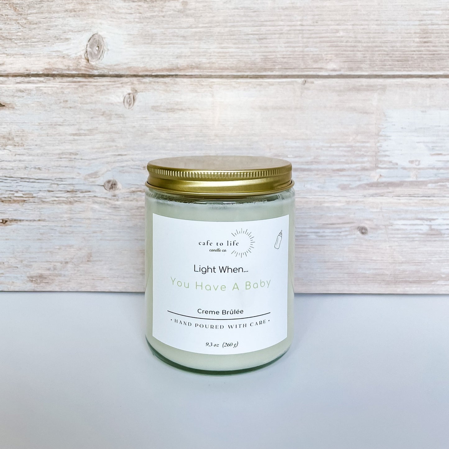 Glass candle with gold lid. Twine with a thank you tag and a heart. Label says, “Light When… You Have A Baby.”