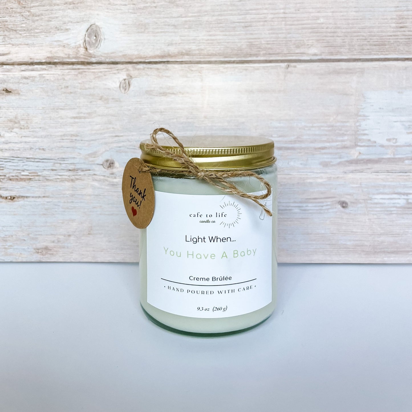 Candle with gold top, twine, thank you tag with a heart. Label says, “Light When… You Have A Baby.”