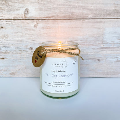 Lit glass candle jar with a thank you tag. Label says, “Light When… You Get Engaged.” 
